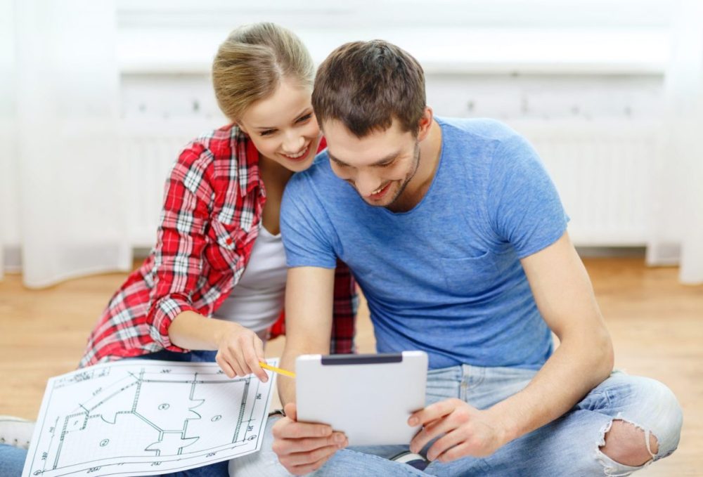 Un couple examine des plans de maison et des documents immobiliers avant son premier rendez-vous avec LGM Immobilier.