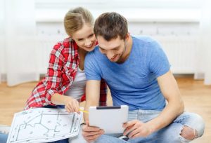 Un couple examine des plans de maison et des documents immobiliers avant son premier rendez-vous avec LGM Immobilier.